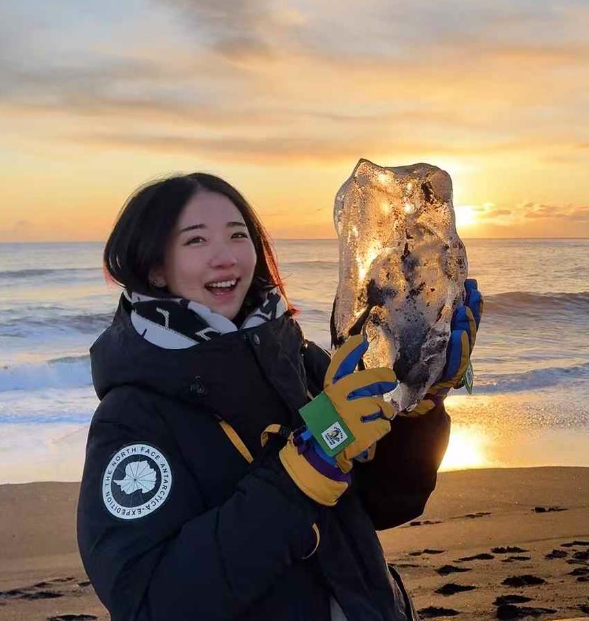 Yiyi holding a piece of ice at sunset in Iceland